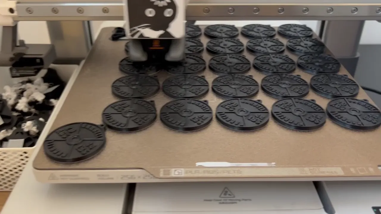 Cama de la Bambu Lab A1 llena de chapas impresas en negro durante una tanda de producción
