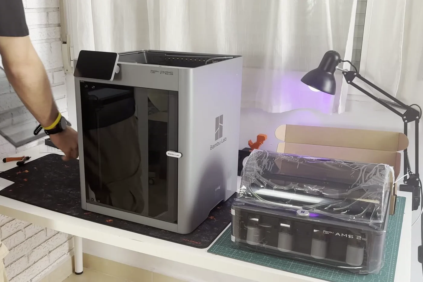Mi Bambu Lab P2S recién montada en el taller, junto al AMS 2 Pro todavía embalado