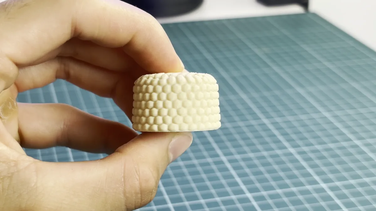 Pomo impreso en 3D en PLA crema con textura de agarre en relieve, sujeto con la mano