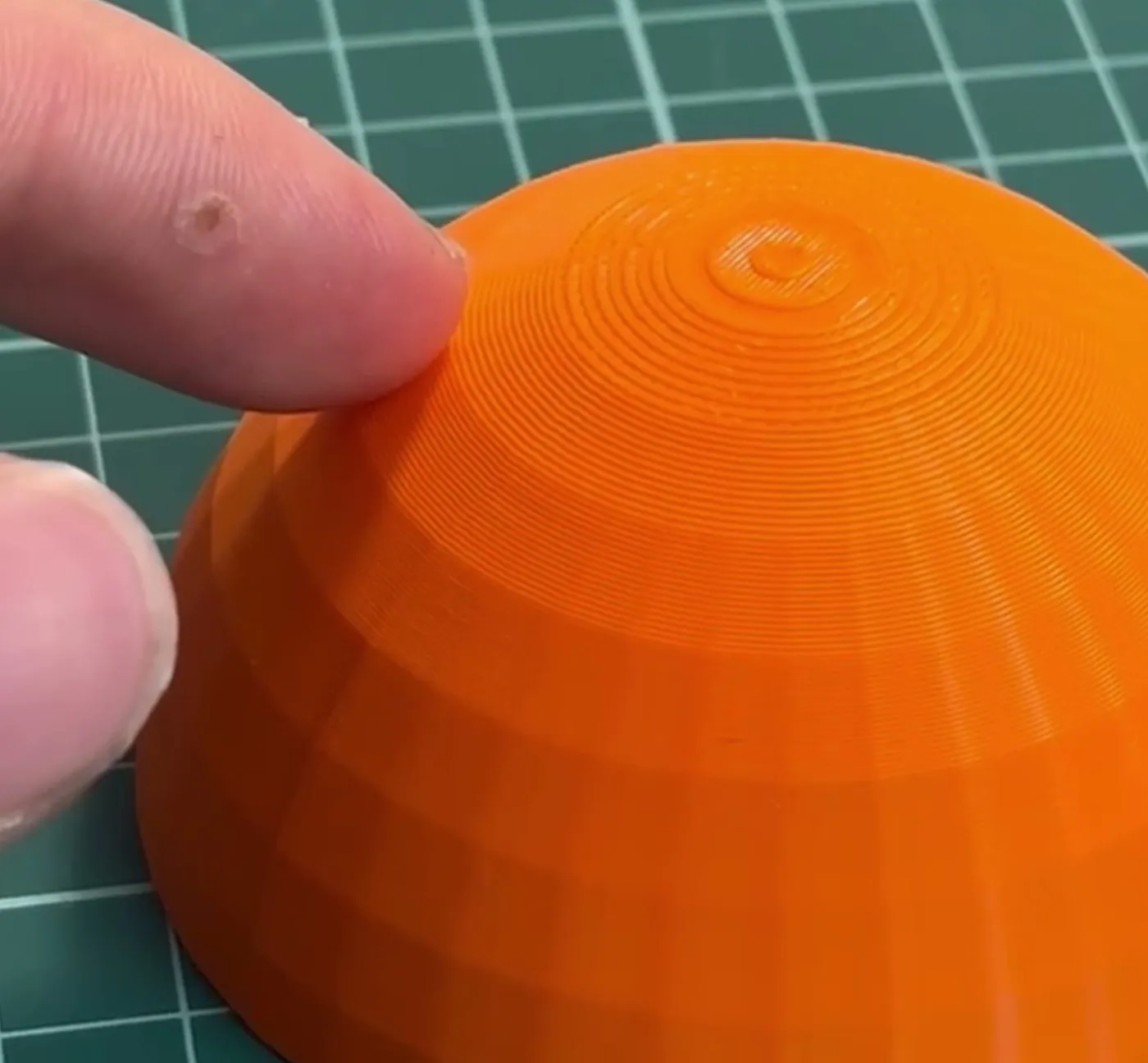 Semiesfera naranja impresa en 3D con los escalones de las capas marcados en la parte de arriba