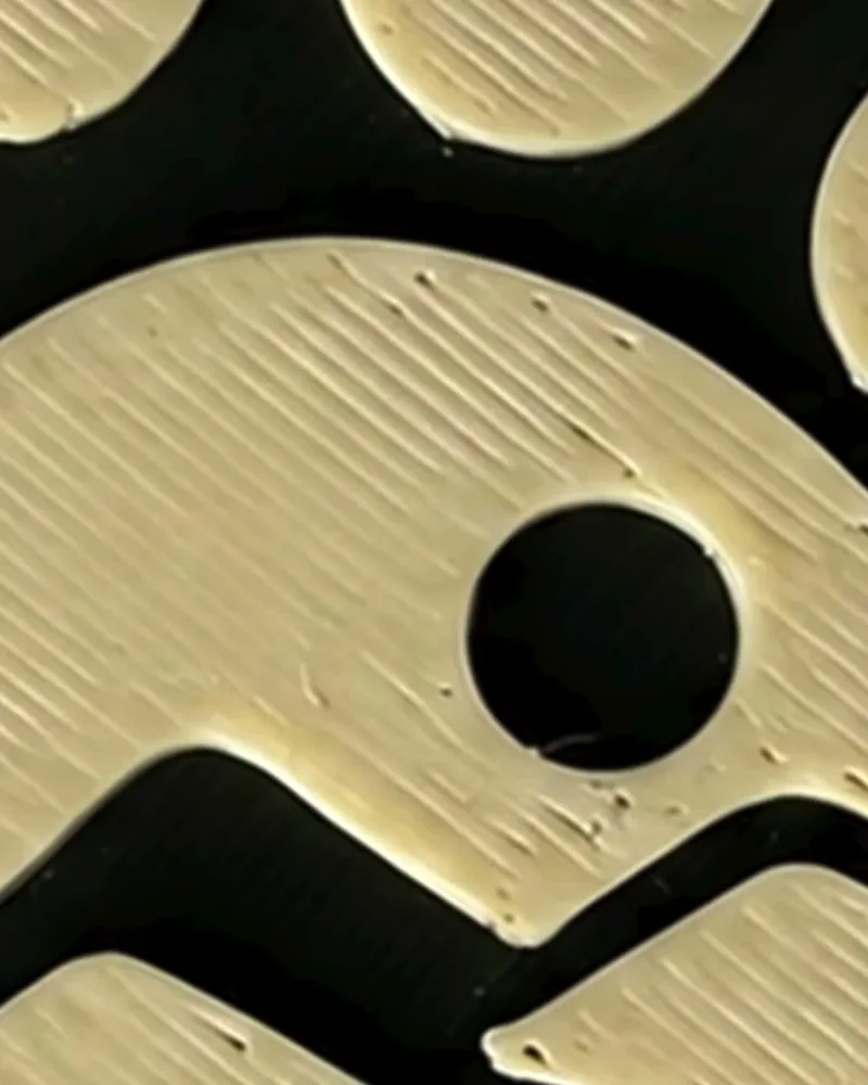 Primer plano de una pieza impresa en 3D de color crema con líneas marcadas y huecos en la superficie