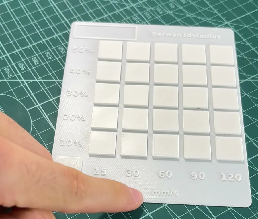 Placa blanca del test de planchado sobre una alfombrilla de corte: 25 cuadrados con el flujo del 10 al 50 por cien en las filas y la velocidad de 15 a 120 mm/s en las columnas, más un cuadrado OFF en la esquina