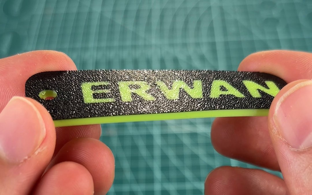 El llavero liso de TPU visto por la cara que tocaba la cama: las letras ERWAN en verde a ras del fondo negro y el canto verde