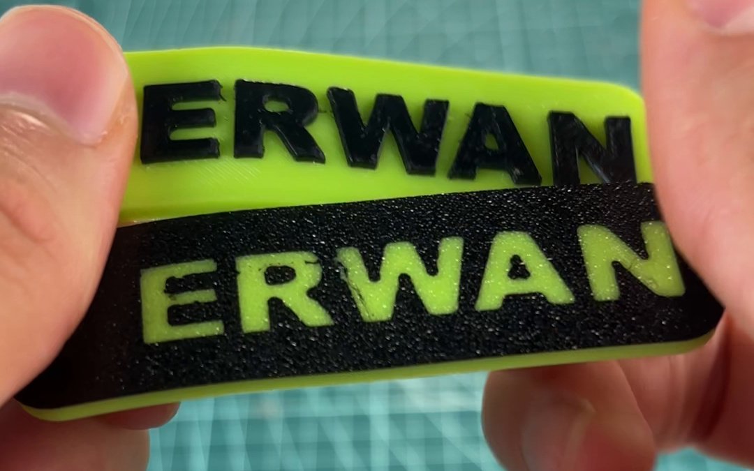 Los dos llaveros de TPU con el nombre ERWAN: arriba el de relieve, verde con las letras negras, y abajo el liso, negro por la cara de la cama con las letras verdes
