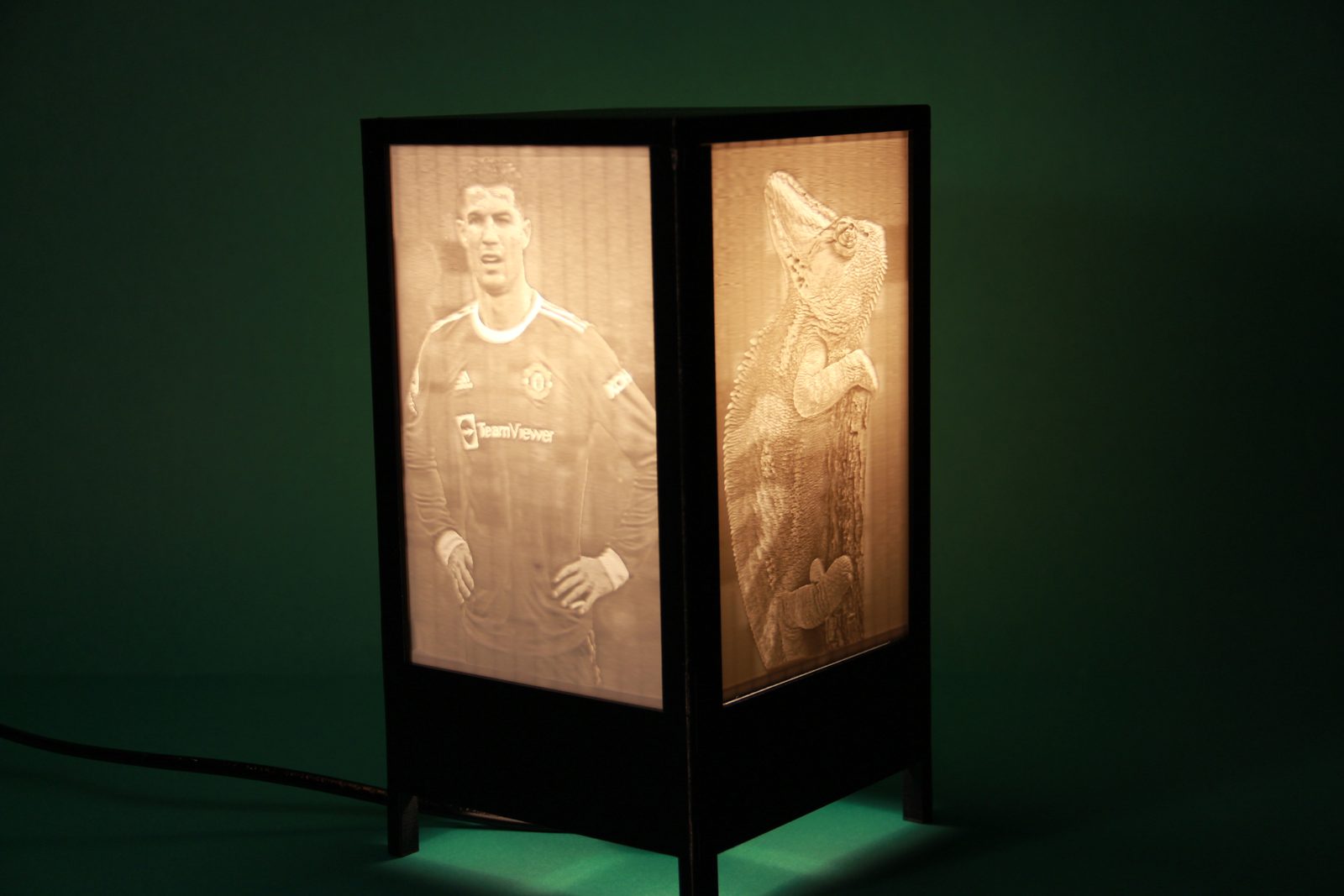 La lámpara de litofanías impresa en 3D encendida, con la estructura negra y dos de sus cuatro litofanías iluminadas