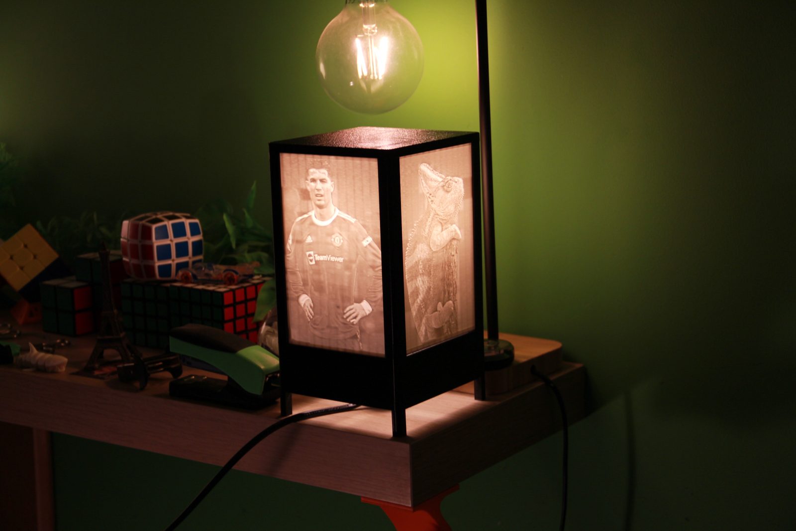 La lámpara de litofanías encendida sobre una estantería, en una habitación con poca luz