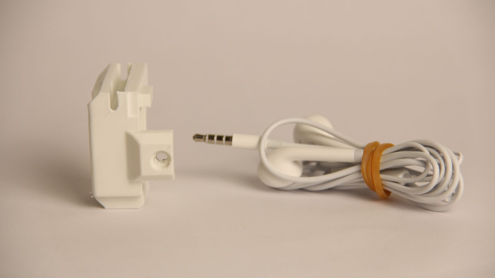 La pieza principal del sistema de timelapse junto a unos auriculares de cable blancos con conector de 3,5 mm